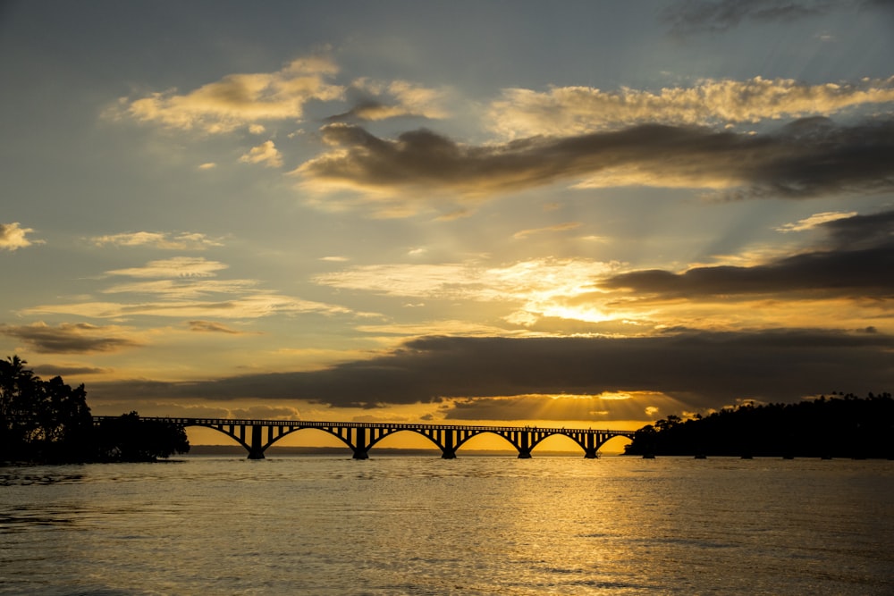 El sol se está poniendo sobre un puente sobre un cuerpo de agua