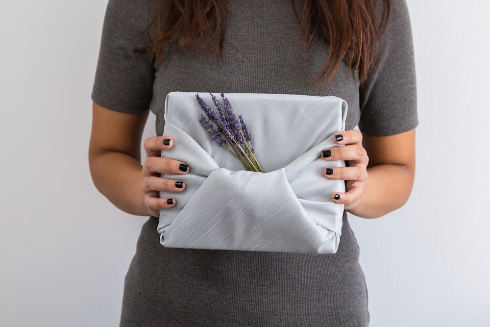 Mujer con camisa gris sosteniendo un bolso de cuero blanco