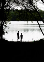 silhouette of couple standing near body of water during daytime