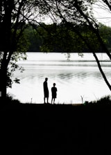 silhouette of couple standing near body of water during daytime