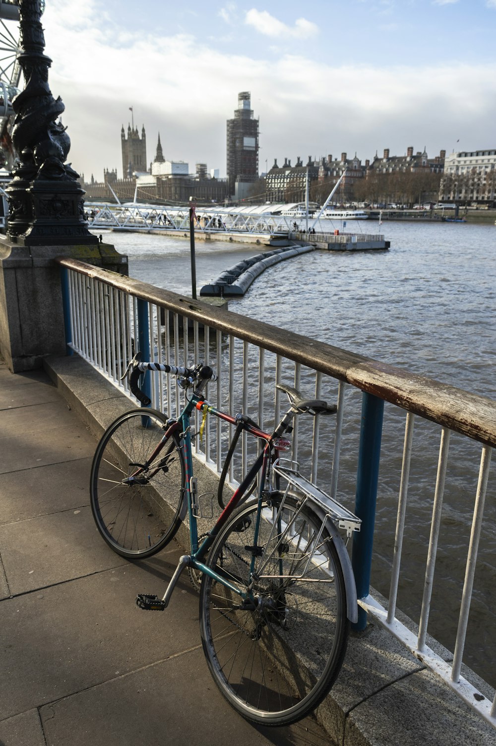 black and red city bike parked beside gray metal railings near body of water during daytime