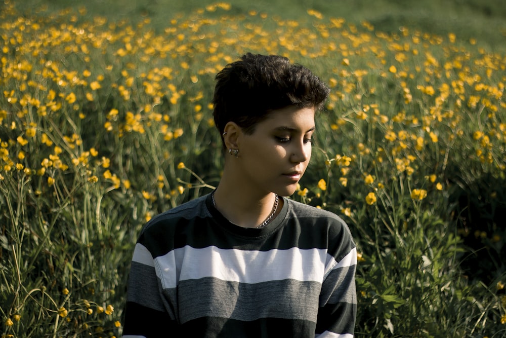 boy in black and white striped crew neck shirt standing on yellow flower field during daytime