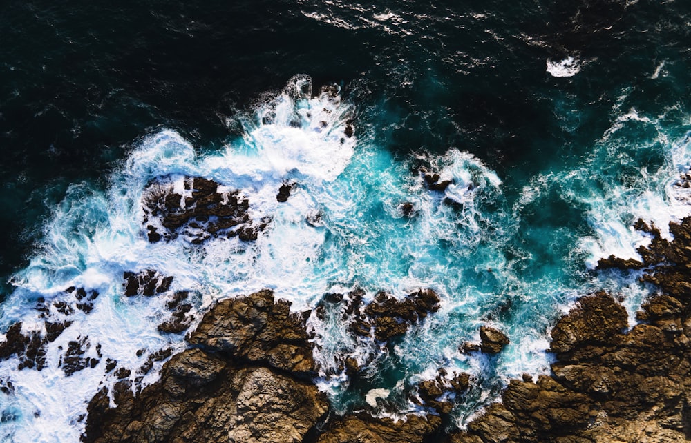 Le onde d'acqua colpiscono le rocce durante il giorno