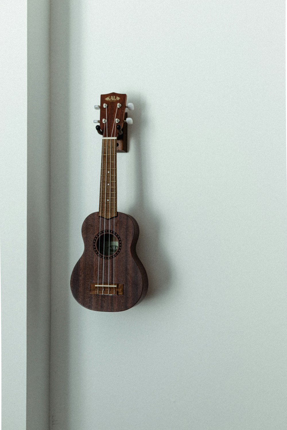 Guitarra acústica marrón sobre pared blanca