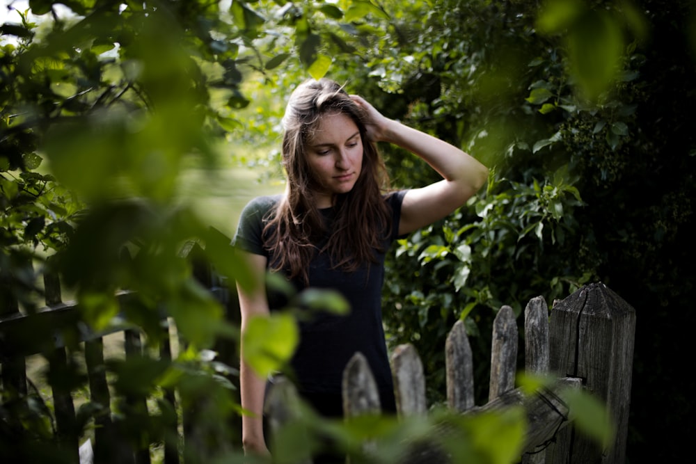 woman in black tank top standing beside wooden fence during daytime