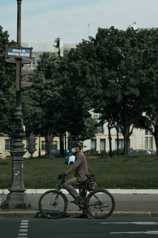 man in black jacket riding bicycle during daytime in Invalides France