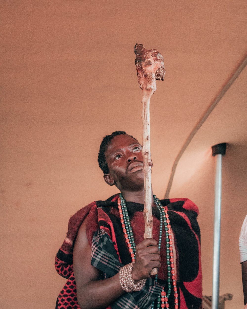 man in red and black scarf holding white stick