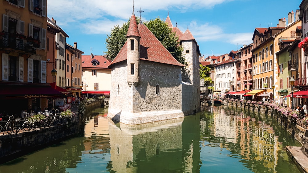 Weißes und braunes Betongebäude am Fluss unter blauem Himmel tagsüber