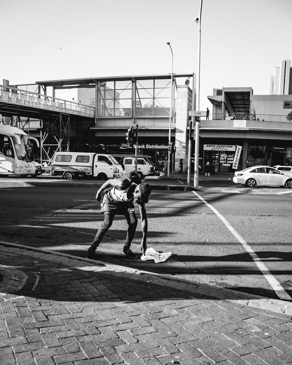 grayscale photo of man in t-shirt and shorts walking on pedestrian lane