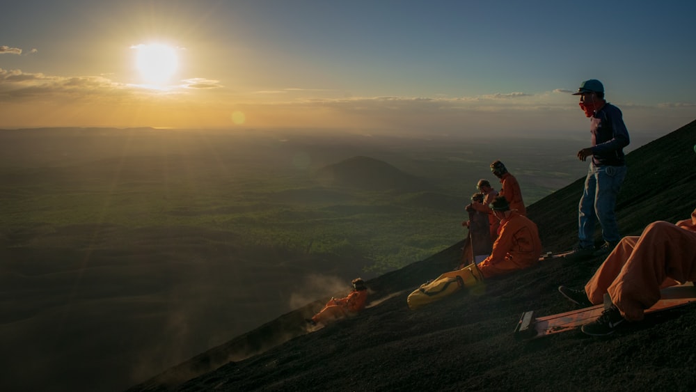 3 person sitting on brown rock during daytime