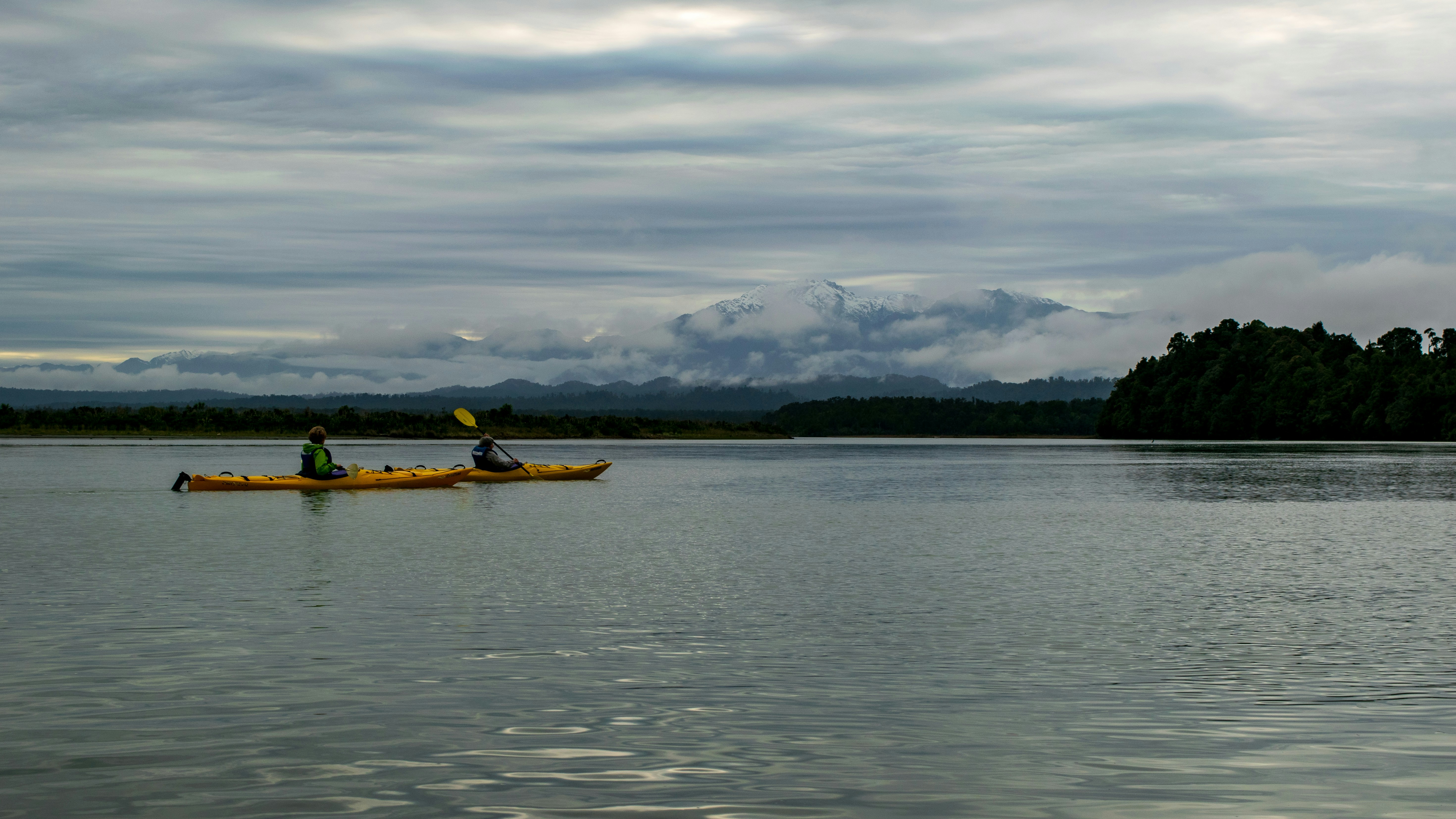 yellow boat on body of water during daytime, Kayaking on the Okarito Lagoon, with the Southern Alps in the background