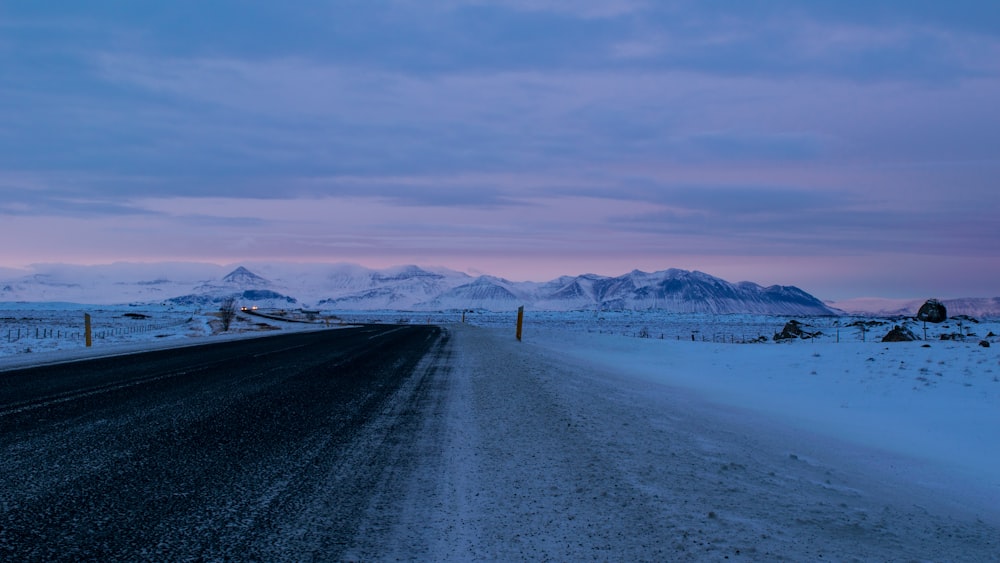 gray road near snow covered mountain during daytime