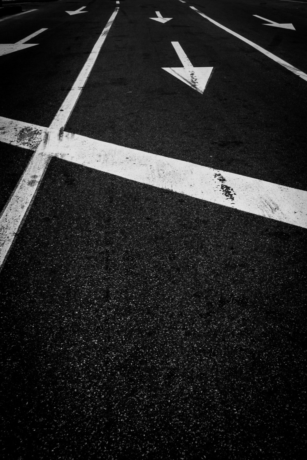 white arrow sign on black and white asphalt road