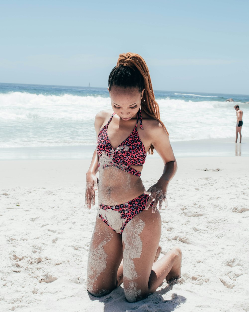 woman in black and red floral bikini standing on beach during daytime