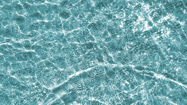 Clear water with intricate patterns of sunlight creating shimmering reflections and textures.