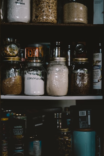 two clear glass jars on white shelf