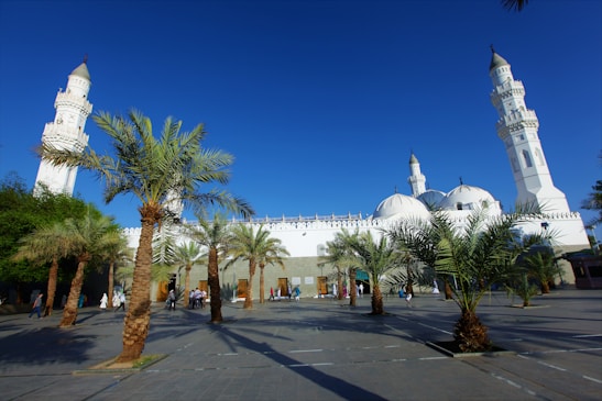 A peaceful mosque courtyard with pilgrims praying under a clear sky.