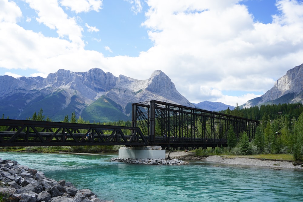 black wooden bridge over river near mountain range