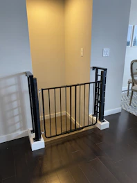 A no-drill pressure-mounted safety gate installed at the top of a staircase, ensuring child safety.
