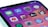 A close-up view of a smartphone screen displaying various app icons on a gradient background. The icons include Messages, App Store, Settings with a notification badge, and Clock, among others.