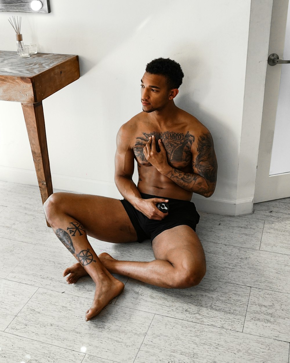 topless man in black shorts sitting on brown wooden seat