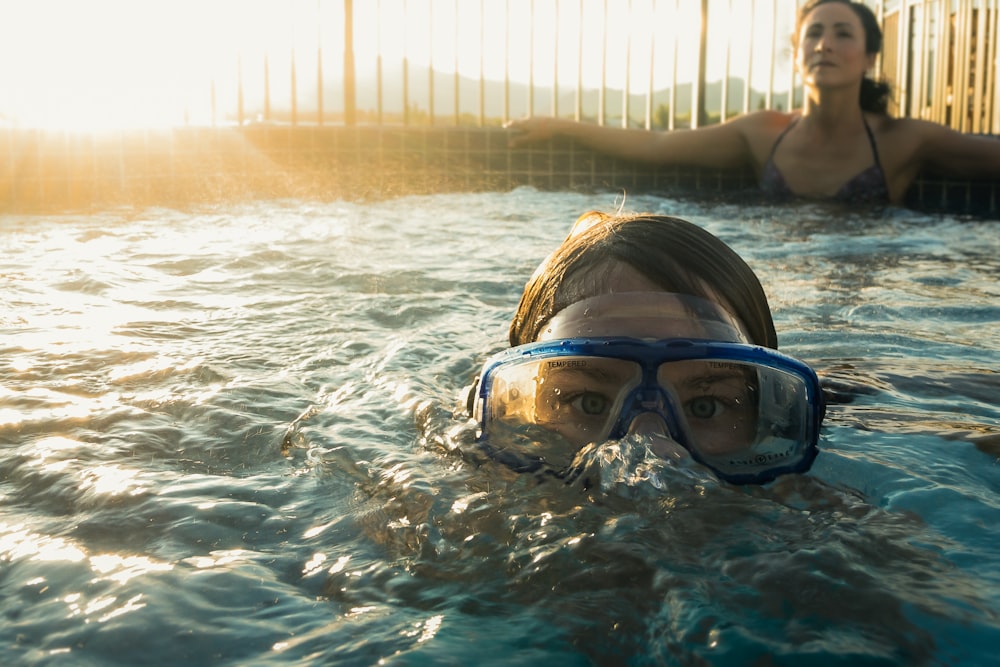 woman in blue swimming goggles in water during daytime