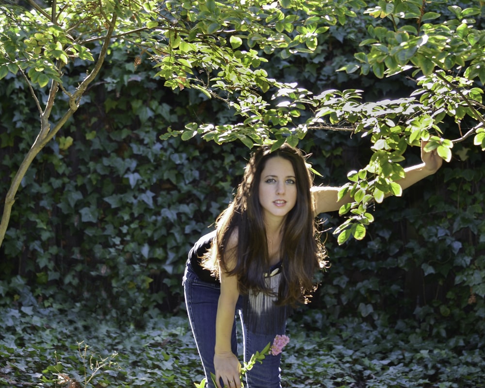 mulher na jaqueta jeans azul que está sob a árvore verde durante o dia