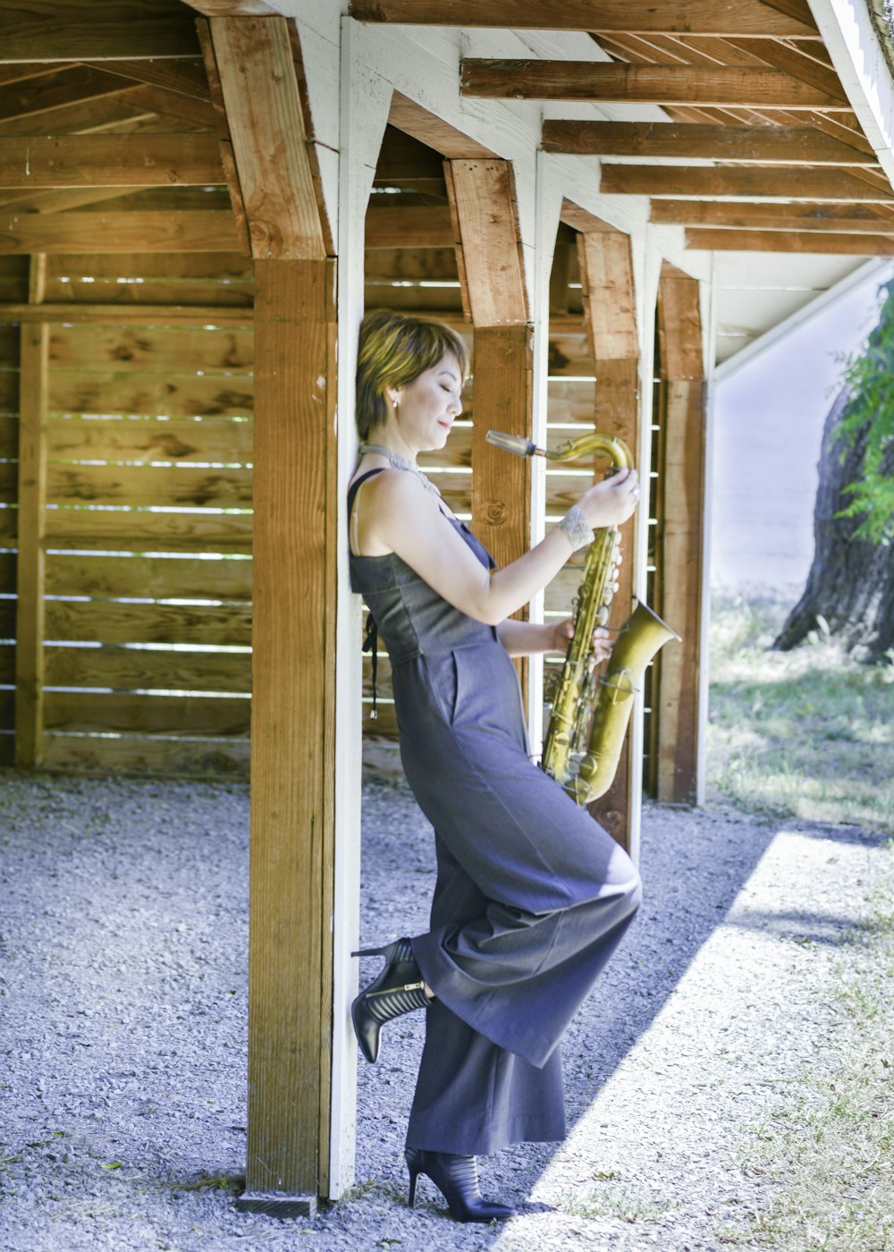 woman in white tank top and blue denim jeans sitting on brown wooden bench during daytime