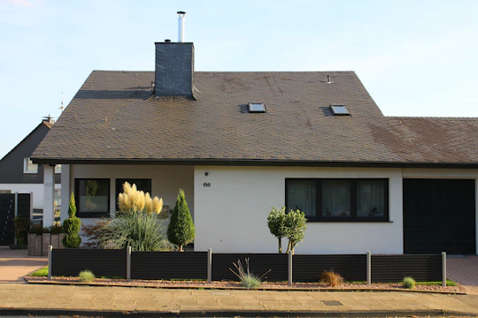 A contemporary shed with gray siding and a flat roof, surrounded by a manicured lawn and garden beds.