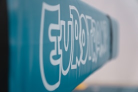 Bold white text reading 'EURO' stenciled on a soft blue background, with a modern font style. The image has a shallow depth of field, causing much of the text to blur into the background.