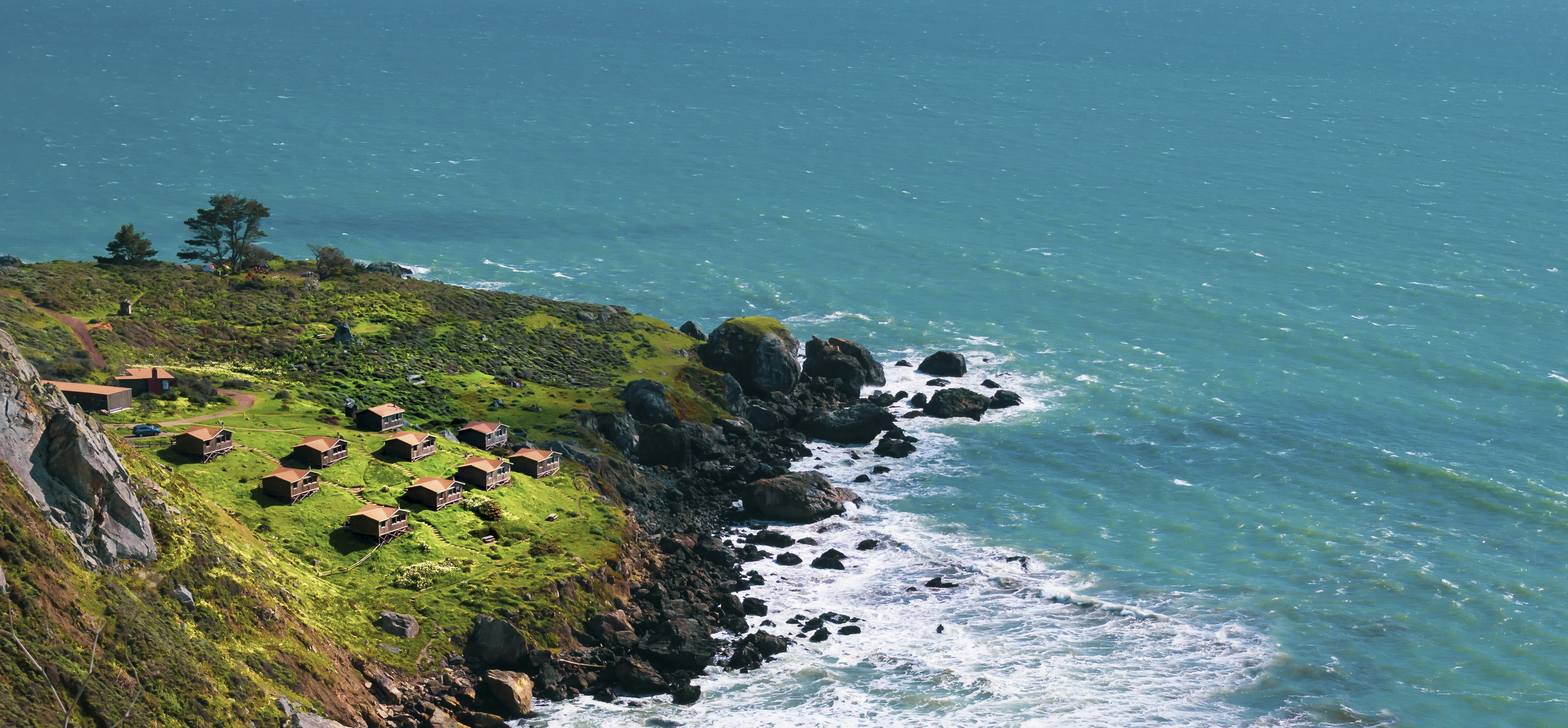 green grass on rock formation near body of water during daytime, Who don