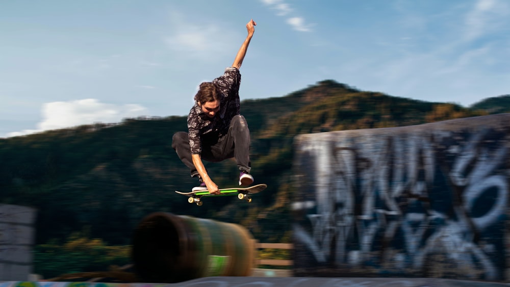 homem na camiseta preta e calças pretas segurando skate