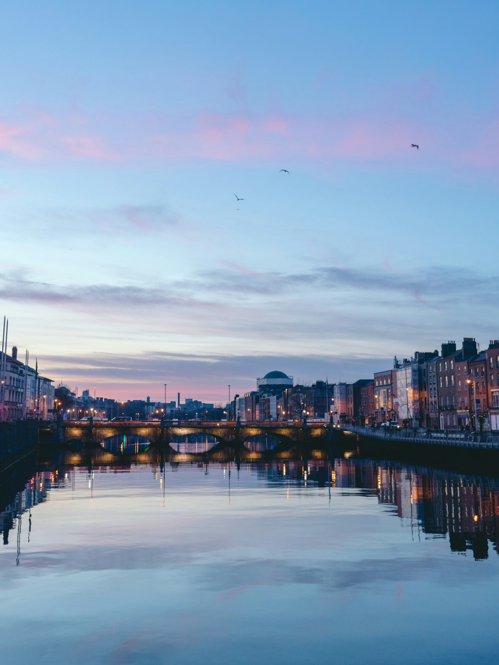 body of water between buildings during sunset