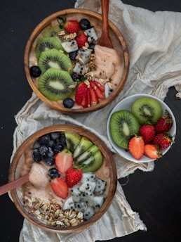 sliced kiwi and strawberry in brown wooden bowl