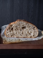 A rustic loaf of bread with a crunchy crust resting on a wooden board.