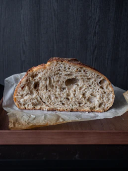 Close-up of a rustic sourdough loaf resting on a wooden board beneath a soft archway