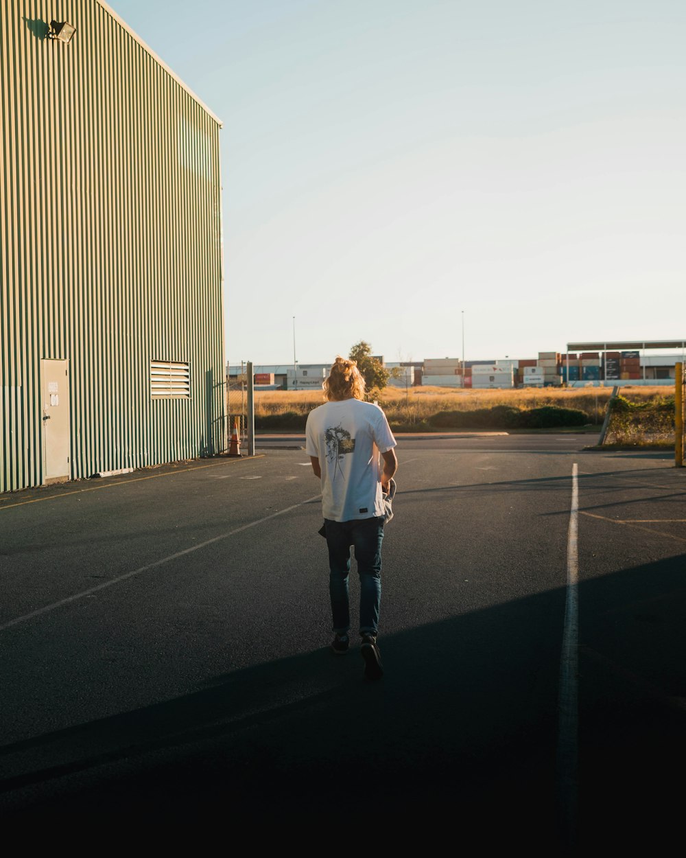 man in white dress shirt and black pants walking on gray asphalt road during daytime