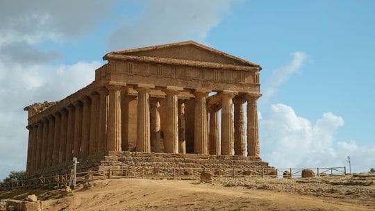 brown concrete building under white clouds during daytime in Temple of Concordia Italy