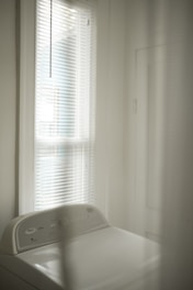 white window blinds near white bed