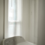 white window blinds near white bed