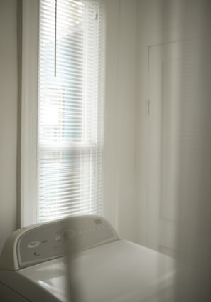 white window blinds near white bed