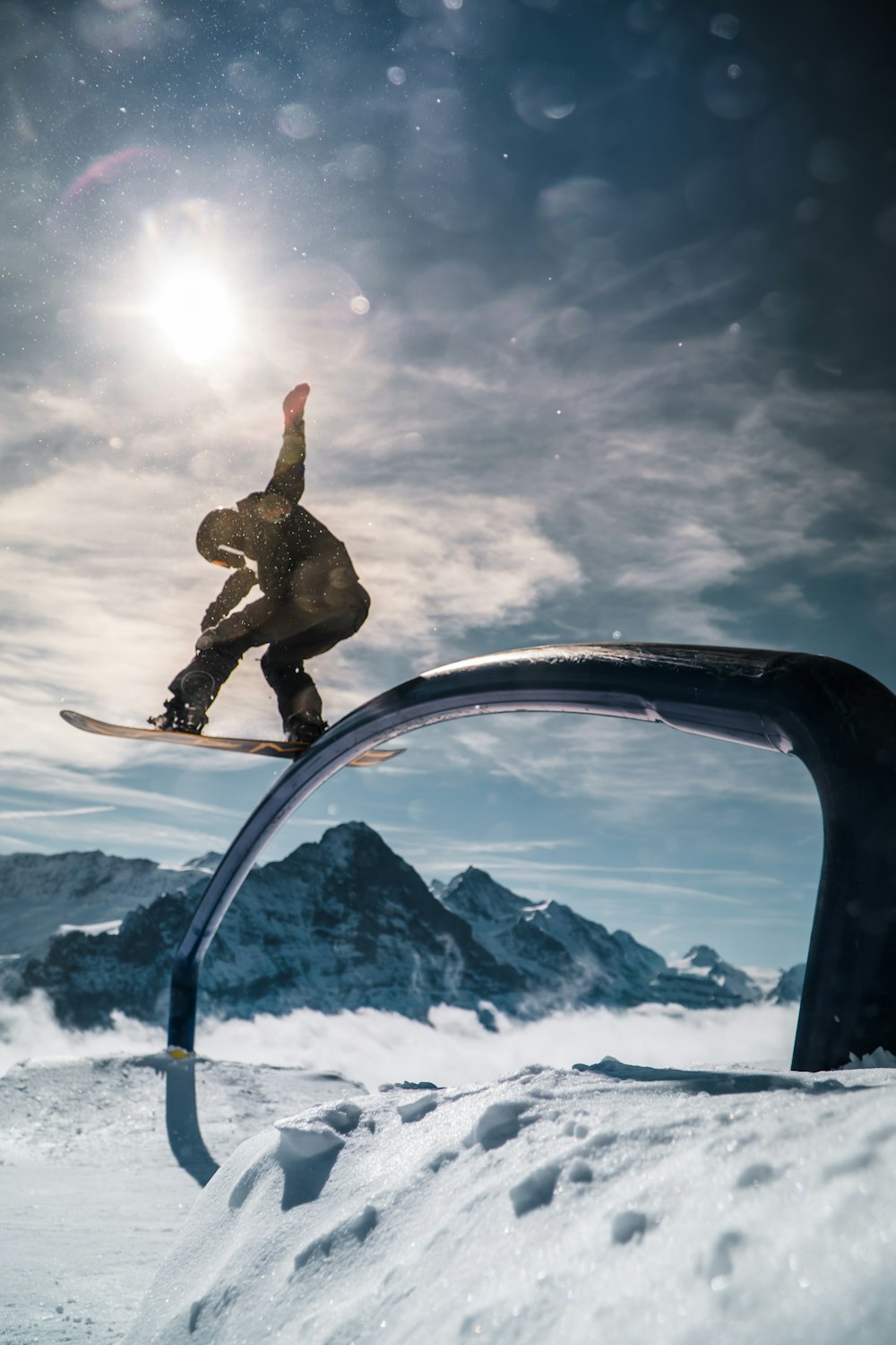 man in black jacket and pants jumping on snow covered ground under blue sky with white