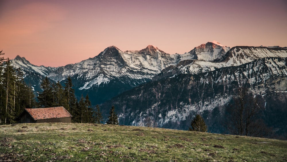 brown wooden house near snow covered mountain during daytime