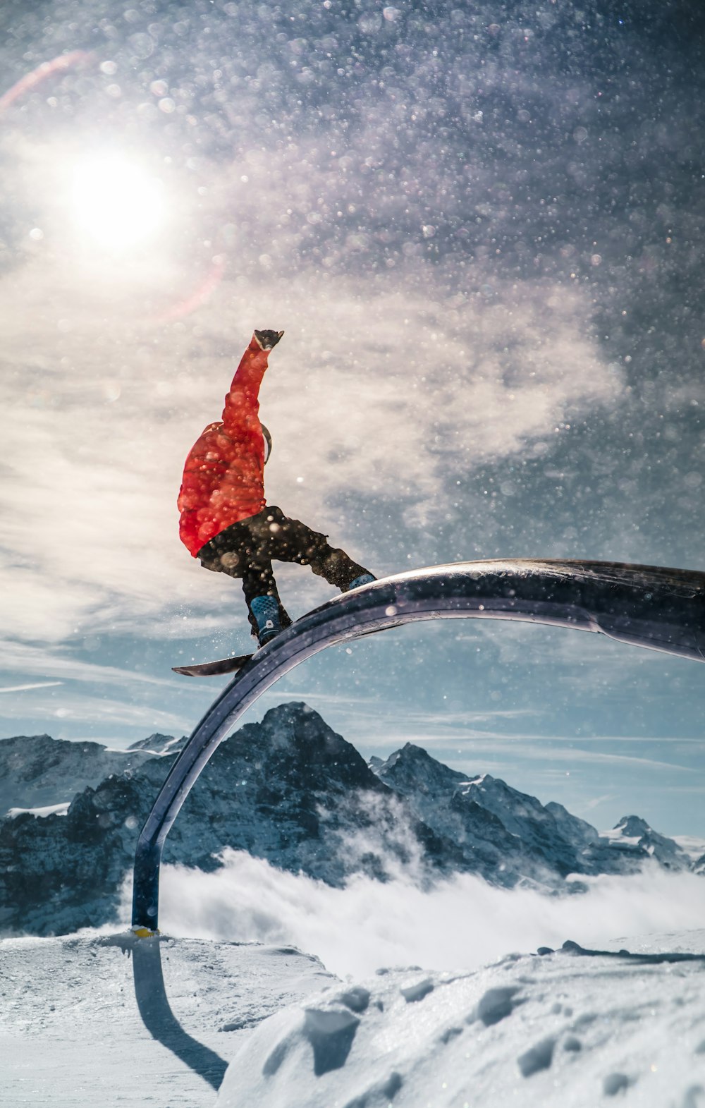 man in red hoodie and blue denim jeans standing on black metal bar during daytime