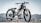 A vintage-style motorcycle is prominently displayed against an out-of-focus urban or mountainous landscape. The motorcycle has a sleek green and black design with number 77 painted on its fuel tank. It features a round headlight and spoked wheels, giving it a classic, retro aesthetic.
