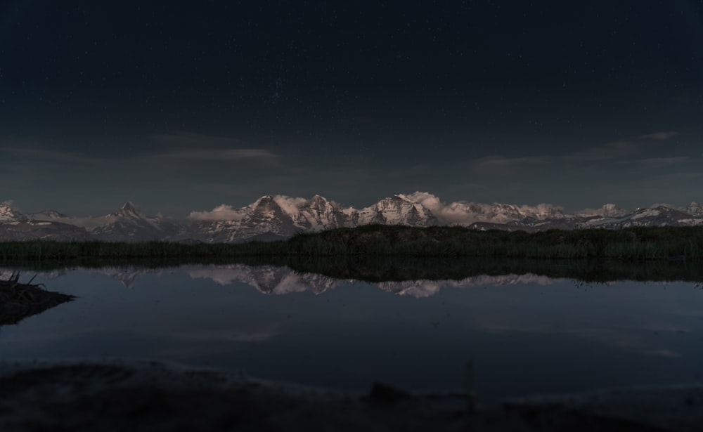 snow covered mountain near lake during night time