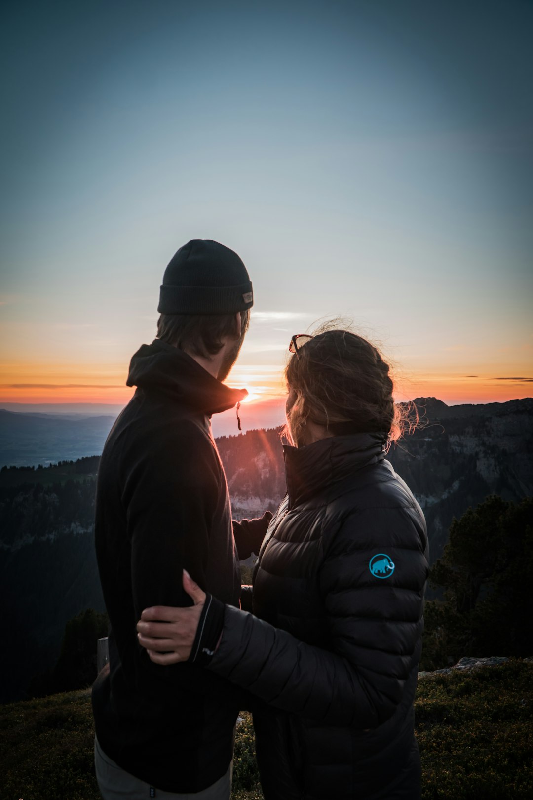 man and woman standing on top of mountain during sunset