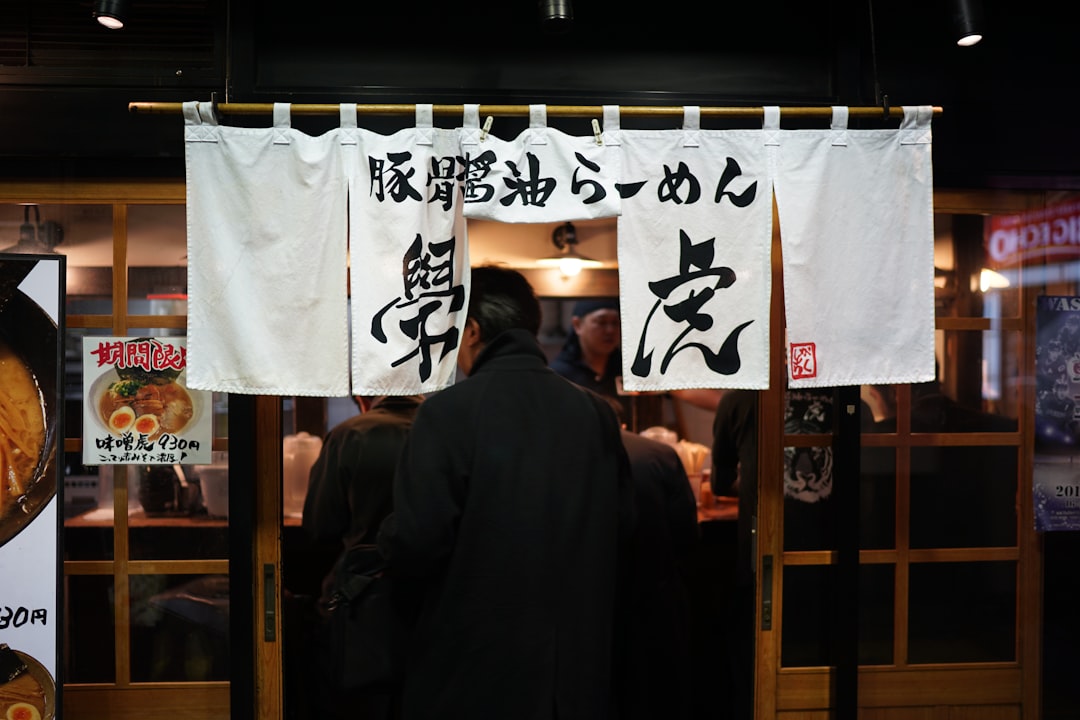 man in black jacket standing near brown wooden door