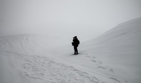 person in black jacket and pants walking on snow covered ground during daytime in Bcharré Lebanon