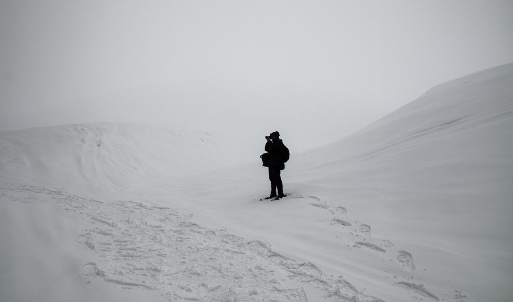 person in black jacket and pants walking on snow covered ground during daytime